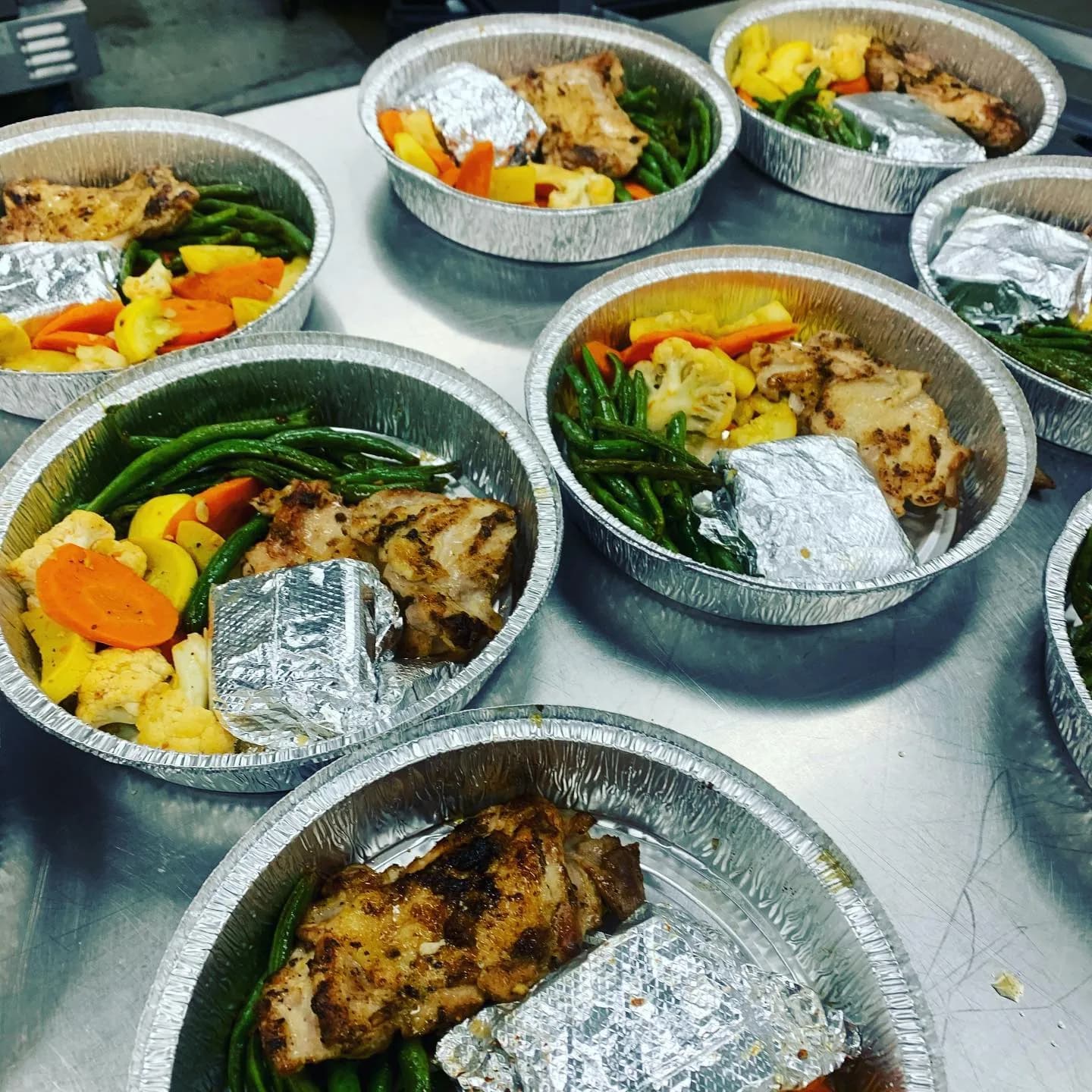 Individually packaged hot meals with grilled chicken and vegetables by KMR Gourmet Catering